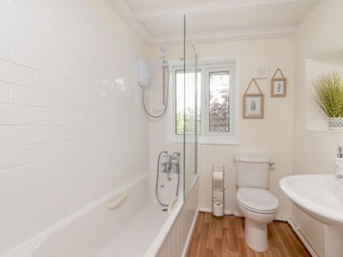 A bathroom with a bathtub shower combo toilet sink and framed pictures on the wall at Holly Cottage Middle Tysoe in Tysoe