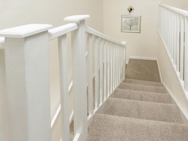 A carpeted staircase with white wooden railings and a framed tree picture on the wall at Holly Cottage Middle Tysoe in Tysoe