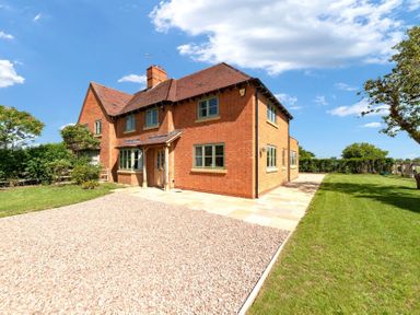 A brick house with a gravel driveway and grass lawn at Mount View in Childswickham