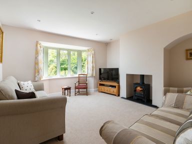 A living room with sofas a wood stove a television and a bay window at Mount View in Childswickham