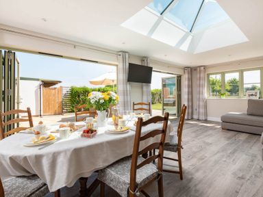 A dining area with a table set for breakfast near large open doors and a skylight at Mount View in Childswickham