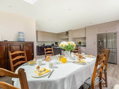 A kitchen with a dining table set for breakfast flowers on table at Mount View in Childswickham
