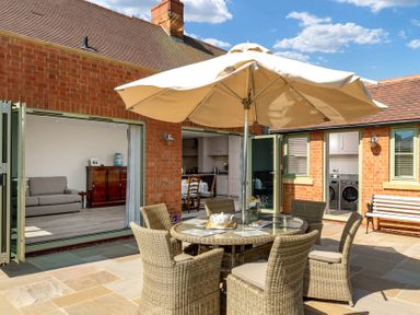 An outdoor patio with a round table and chairs under an umbrella at Mount View in Childswickham