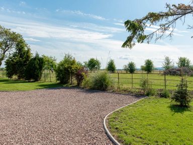 A gravel driveway bordered by grass and shrubs with a metal fence and trees in a rural setting at Mount View in Childswickham