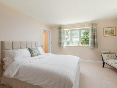 A bedroom with a large bed a window with curtains and a chaise lounge at Mount View in Childswickham