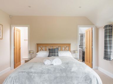 A bedroom with a wooden bed and two open doors showing adjacent rooms at Mount View in Childswickham