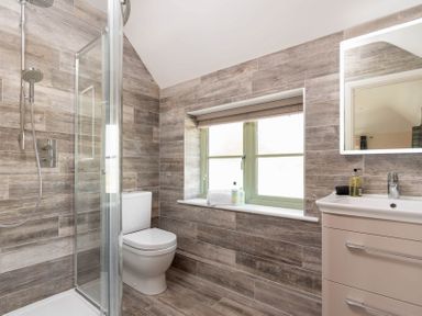 A bathroom with a shower, toilet, sink, and window at Mount View in Childswickham