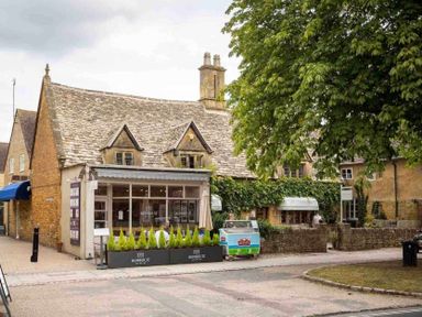 A street view of a stone building with a cafe named number 32 and some greenery at Mount View in Childswickham