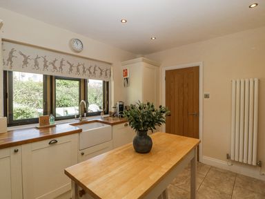 A kitchen with a table and windows at Bell Garden in Stow-On-The-Wold