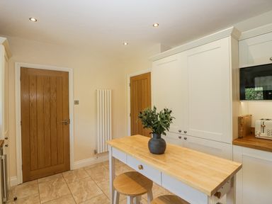 A kitchen with a table and stools at Bell Garden in Stow-On-The-Wold