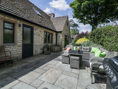 An outdoor seating area with a stone house and furniture at Bell Garden Stow-On-The-Wold
