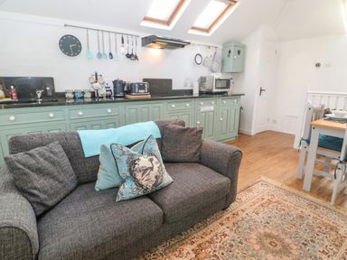A kitchen area with green cabinets sofa and dining table at The Bath House in Blockley
