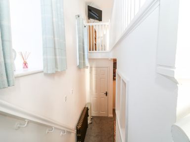A staircase with a white railing a closed door and a wall-mounted television at The Bath House in Blockley