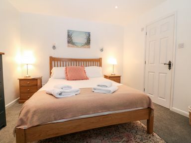 A bedroom with a wooden bed and bedside tables with lamps at The Bath House in Blockley