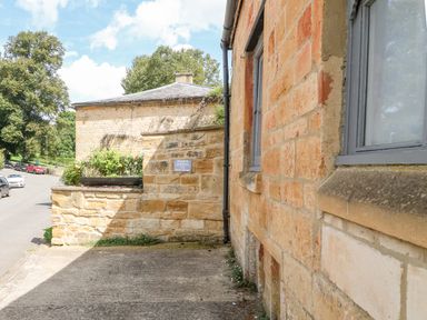 A stone building with gray windows and a small private parking area at The Bath House in Blockley