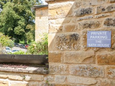 A stone wall with a private parking sign at The Bath House in Blockley
