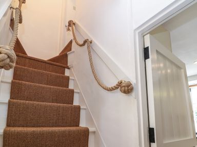 A carpeted staircase with rope handrails and a white door at the bottom at Red Fawn Cottage in Blockley