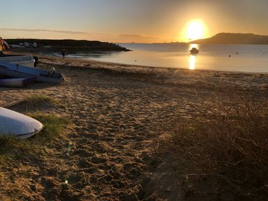 A beach with sand and boats on the shore and a person walking near the water at Beach View House in Wyke Regis