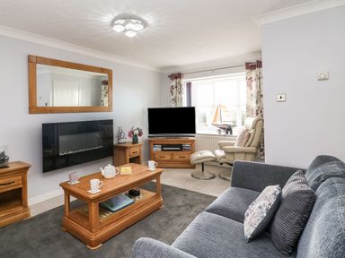 A living room with a sofa armchair coffee table and television at Beach View House in Wyke Regis