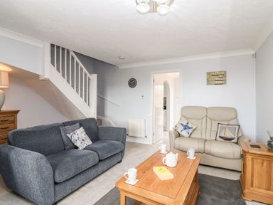 A living room with two sofas a wooden coffee table and stairs at Beach View House in Wyke Regis