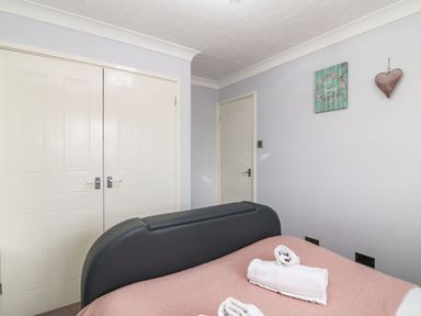 A bedroom with a bed and folded towels on it next to two closed doors at Beach View House in Wyke Regis