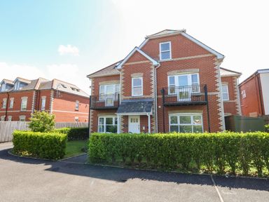 A red brick house with balconies and green hedges in front at Marina Reach Weymouth