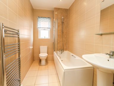 A bathroom with a toilet bathtub shower sink and towel rack at Marina Reach in Weymouth