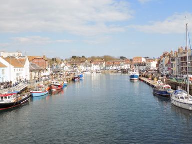A harbor with boats docked along both sides and buildings in the background at Marina Reach in Weymouth