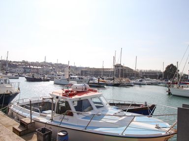 A marina with various boats docked including a small motorboat with a red roof and the name Giffandy at Marina Reach in Weymouth
