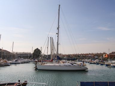 A marina with several boats and yachts docked in the water with buildings in the background at Marina Reach in Weymouth