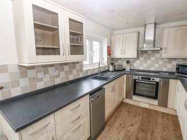 A kitchen with light wood cabinets black countertops a stainless steel oven and dishwasher at The Old Dairy in Maenclochog
