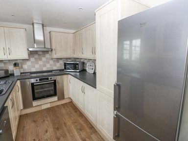 A kitchen with wooden cabinets black countertops a stainless steel oven microwave toaster and refrigerator at The Old Dairy in Maenclochog
