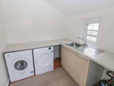 A laundry room with a washing machine dryer sink and countertop at The Old Dairy in Maenclochog