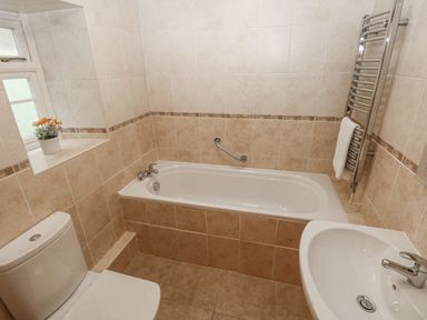 A bathroom with a bathtub toilet sink and towel rack at The Old Dairy in Maenclochog