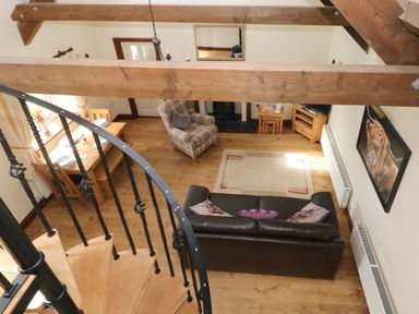 A living room with a dining table chairs sofa armchair rug and spiral staircase at The Old Dairy in Maenclochog