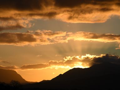 A mountain landscape with the sun setting behind clouds at Caban Cariad in Bryngwran near Bodedern
