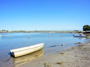 A sandy shore with small boats on calm water and buoys at Caban Cariad in Bryngwran near Bodedern