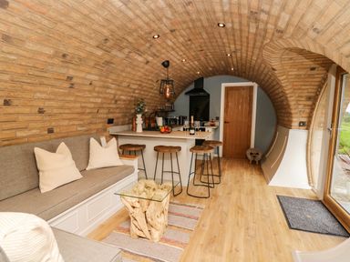 A kitchen and living area with a curved brick ceiling and wooden floor at Tan Y Wawr - Derwen in Llanfair Caereinion