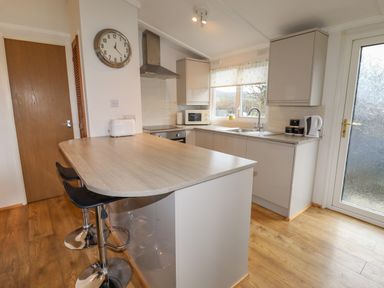 A kitchen with wooden countertop and two bar stools at Wayside Lodge in Aston On Clun