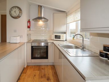 A kitchen with an oven microwave and sink with a window above at Wayside Lodge in Aston On Clun