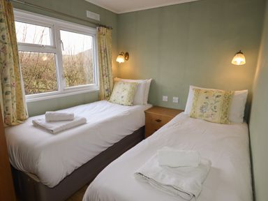 A bedroom with two single beds side by side each with folded towels on top at Wayside Lodge in Aston On Clun