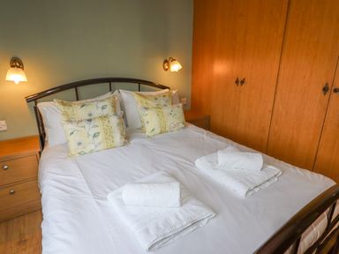 A bedroom with a double bed with floral pillows and folded towels on the bed at Wayside Lodge in Aston On Clun
