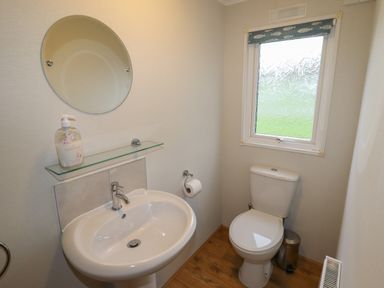 A bathroom with a sink mirror toilet and window at Wayside Lodge in Aston On Clun