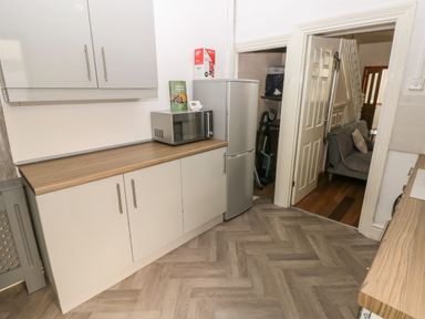 A kitchen with cabinets a microwave a refrigerator and doors leading to adjoining rooms at 5 Pontardulais Road in Llangennech