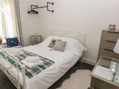 A bedroom with a white metal bed frame white bedding and folded towels on the bed at 5 Pontardulais Road in Llangennech