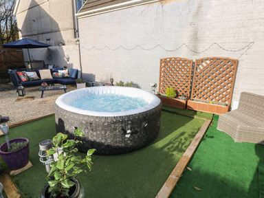 An outdoor patio with an inflatable hot tub and a seating area with cushions at 5 Pontardulais Road in Llangennech