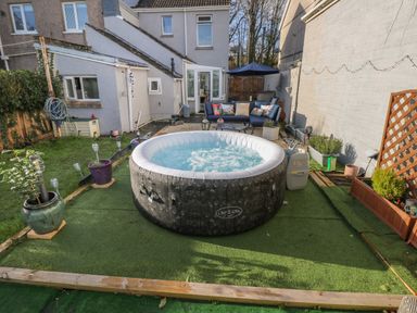 A backyard with a round inflatable hot tub surrounded by potted plants and outdoor seating at 5 Pontardulais Road in Llangennech