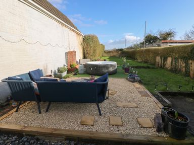 An outdoor garden area with blue seating and a round hot tub on gravel at 5 Pontardulais Road in Llangennech