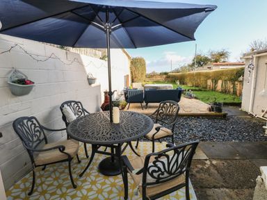 An outdoor patio with a round metal table and four chairs under a large umbrella at 5 Pontardulais Road in Llangennech