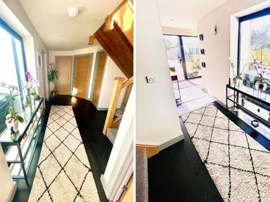 A hallway with a patterned rug a glass shelf holding potted plants wooden doors and stairs at Avalennek in St Newlyn East